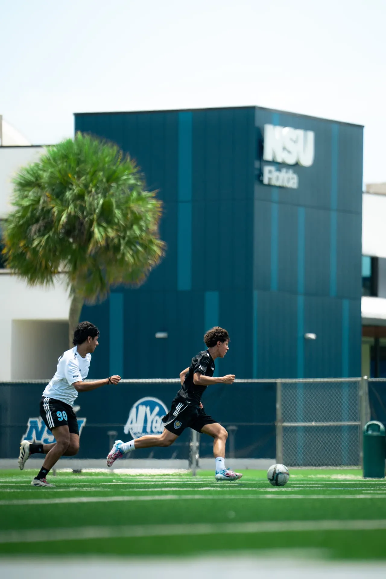 Two players in a footrace chasing the ball at NSU Florida