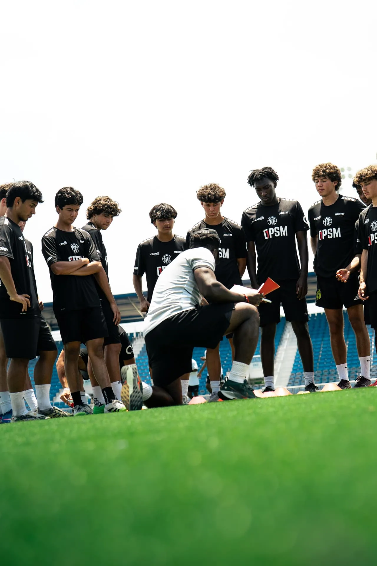 Coach briefing the boys squad in a pitchside huddle