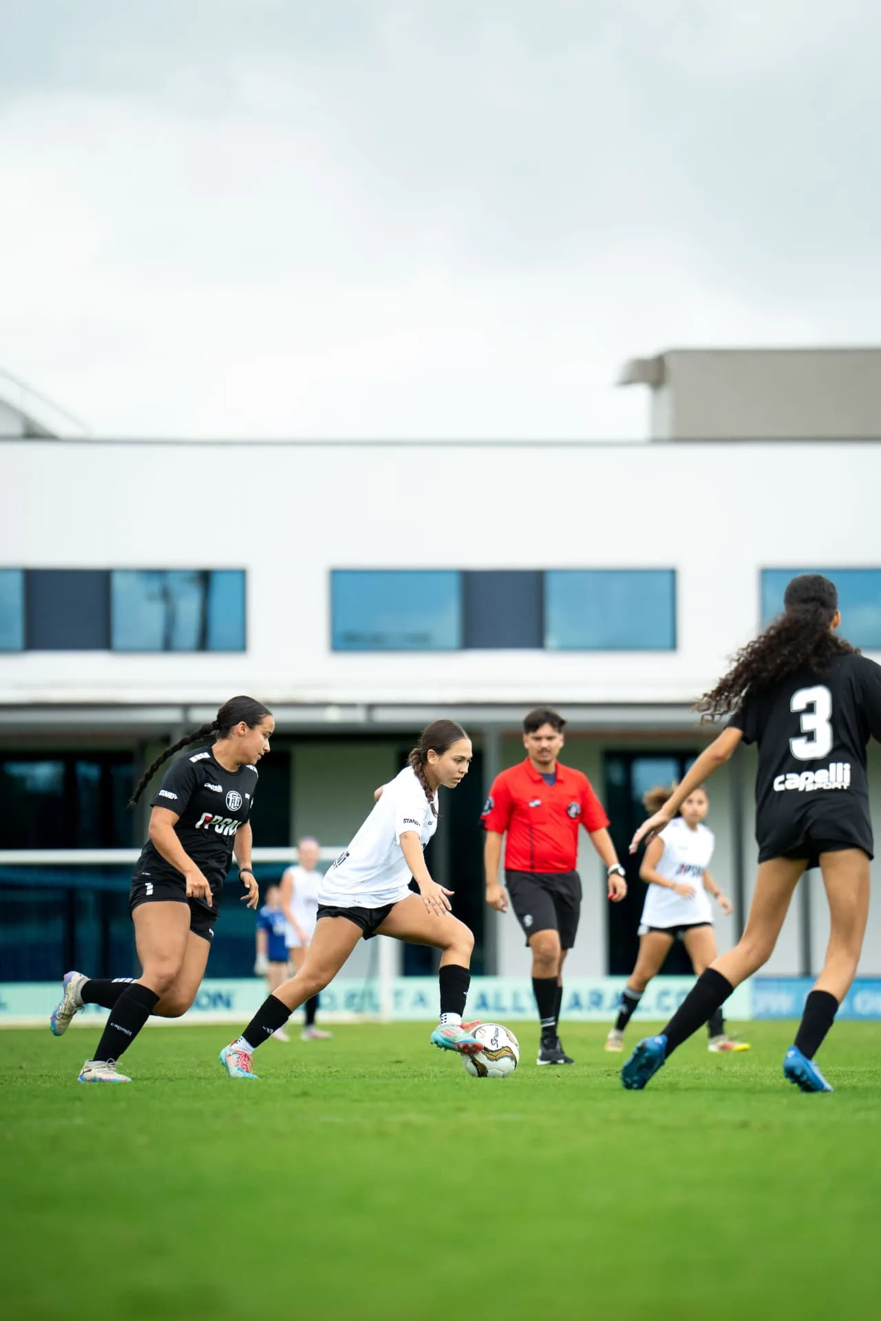 Midfielder in white shielding the ball under pressure