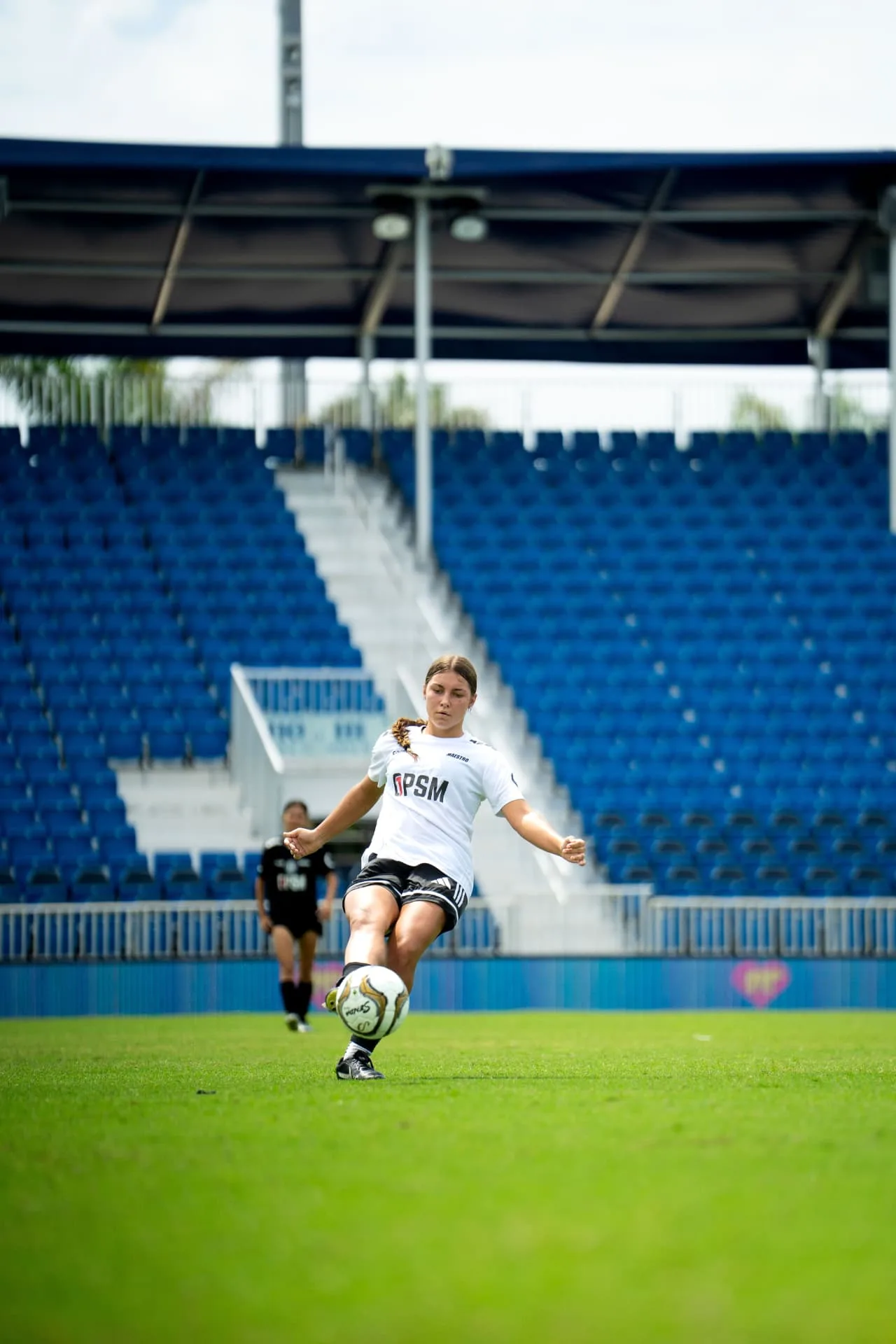 Player in white driving a pass across the pitch