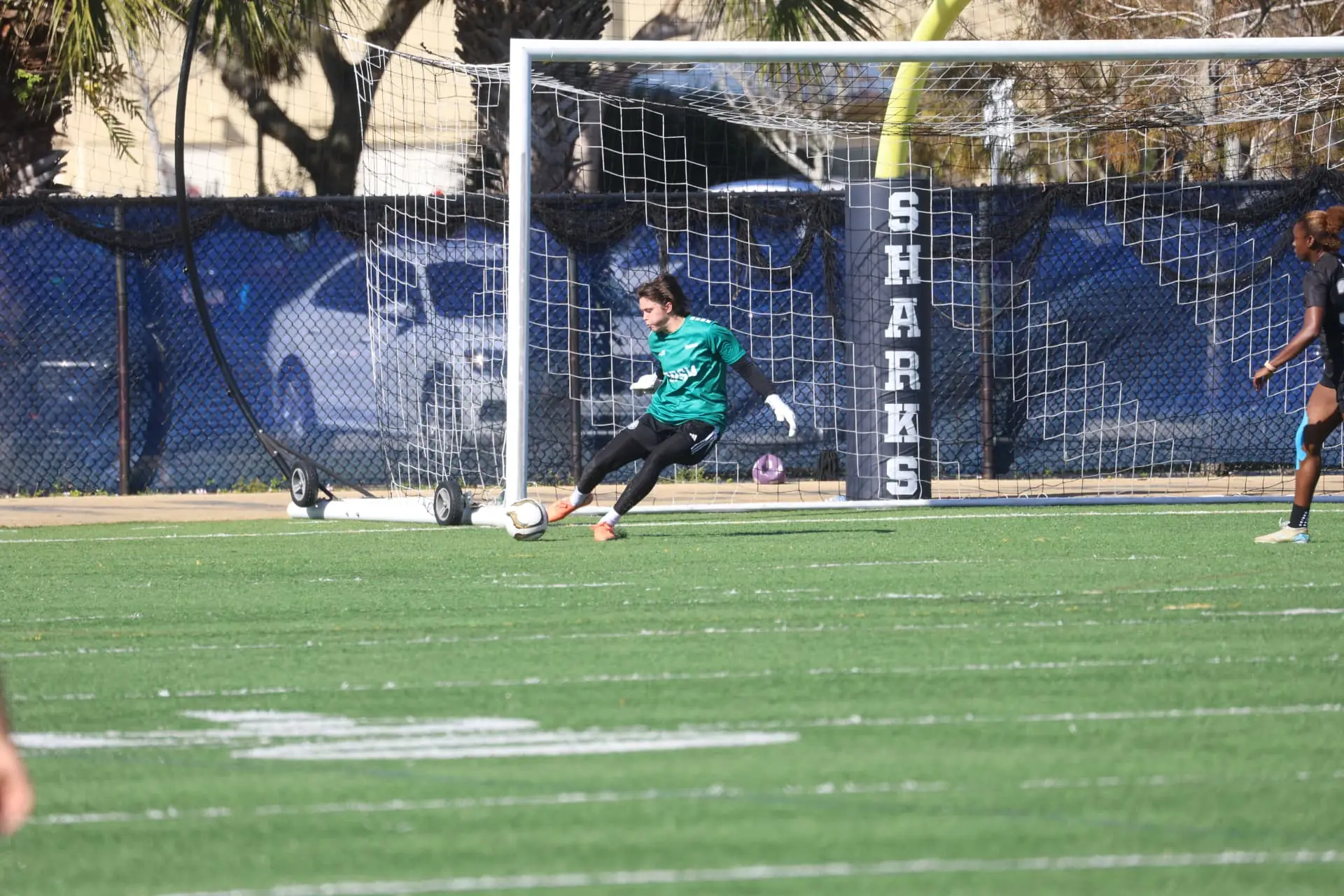 Goalkeeper in green kit distributing from the goal line