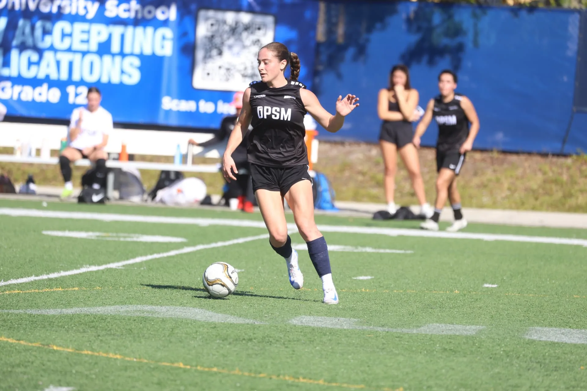 Player in black OPSM kit driving forward with the ball