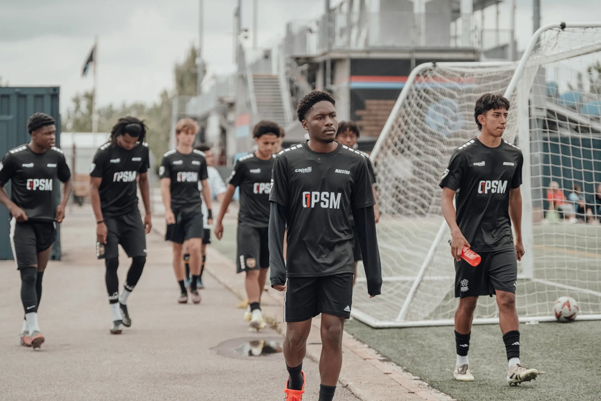Group of players in black OPSM kits walking to the field