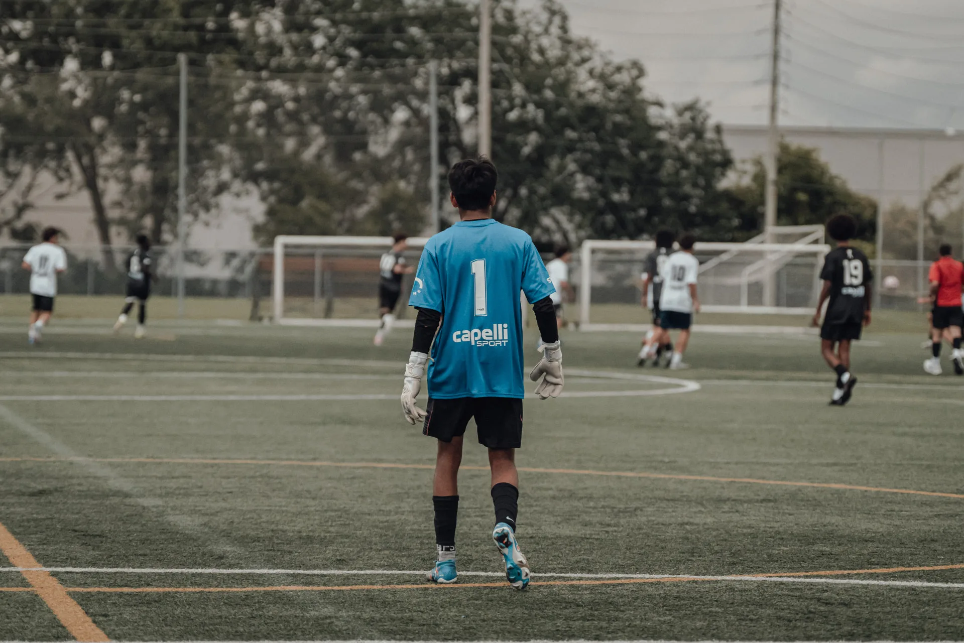 Goalkeeper in blue kit watching play develop upfield