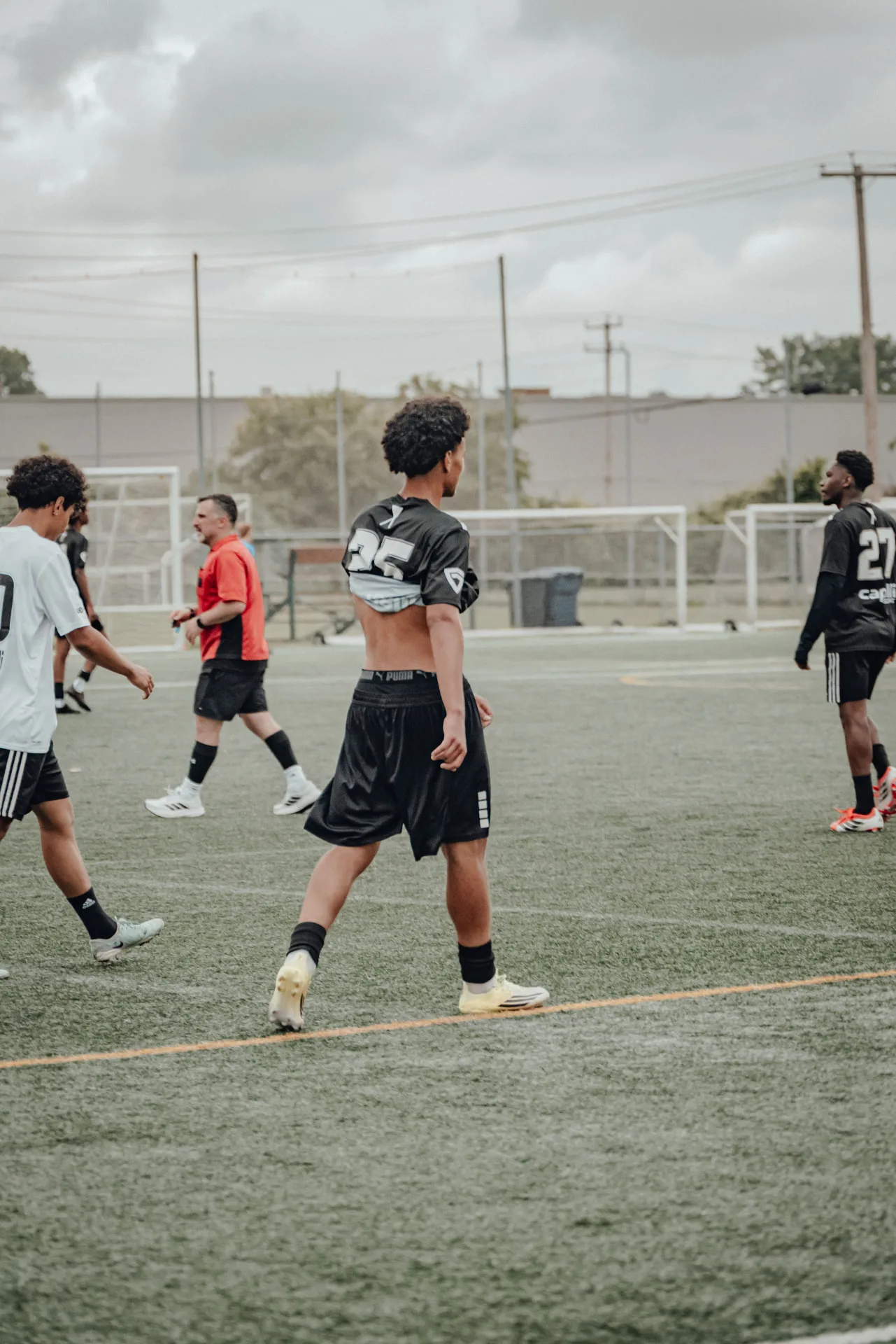 Player in black kit adjusting his shirt during a stoppage
