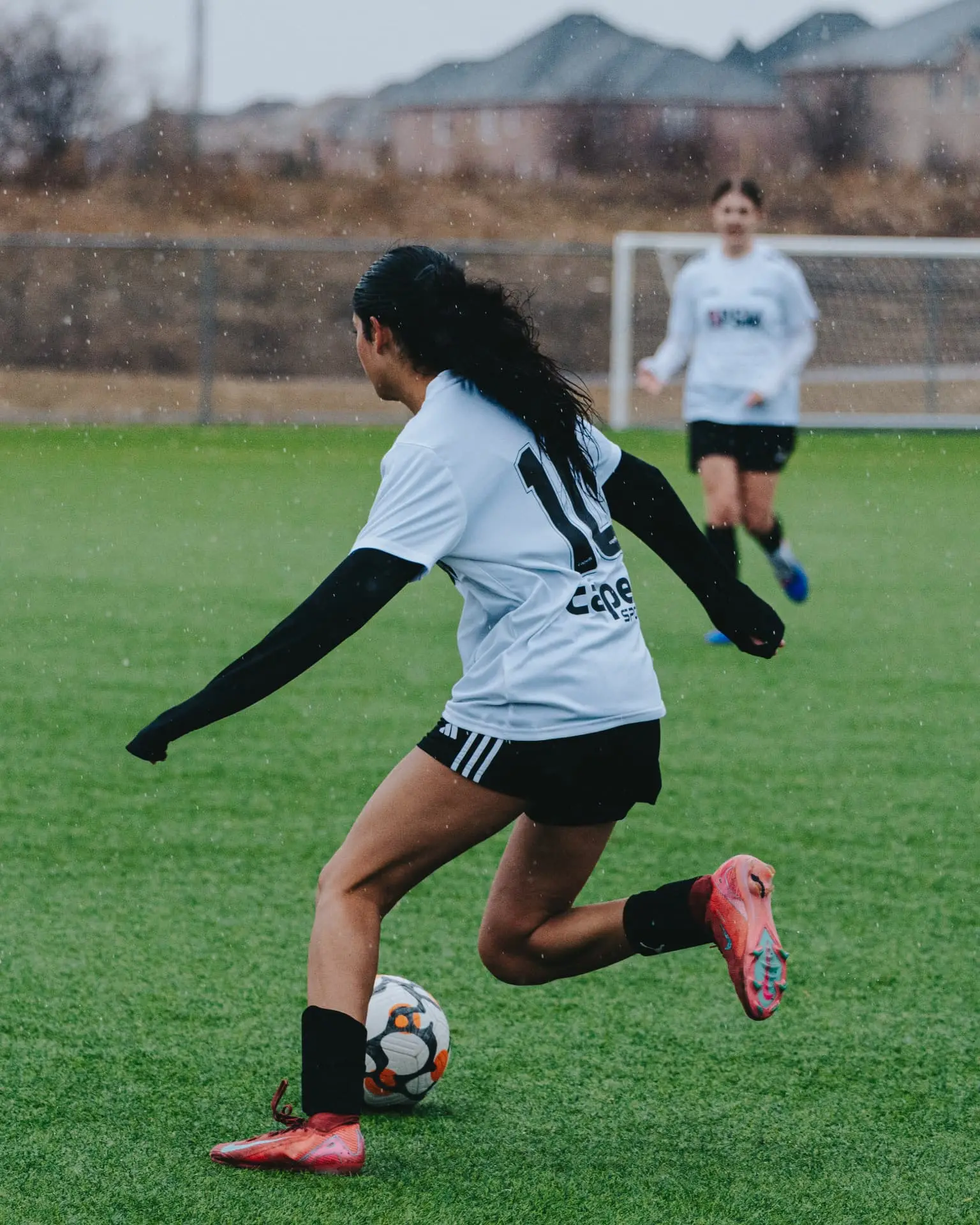 Player striking a pass forward in the rain
