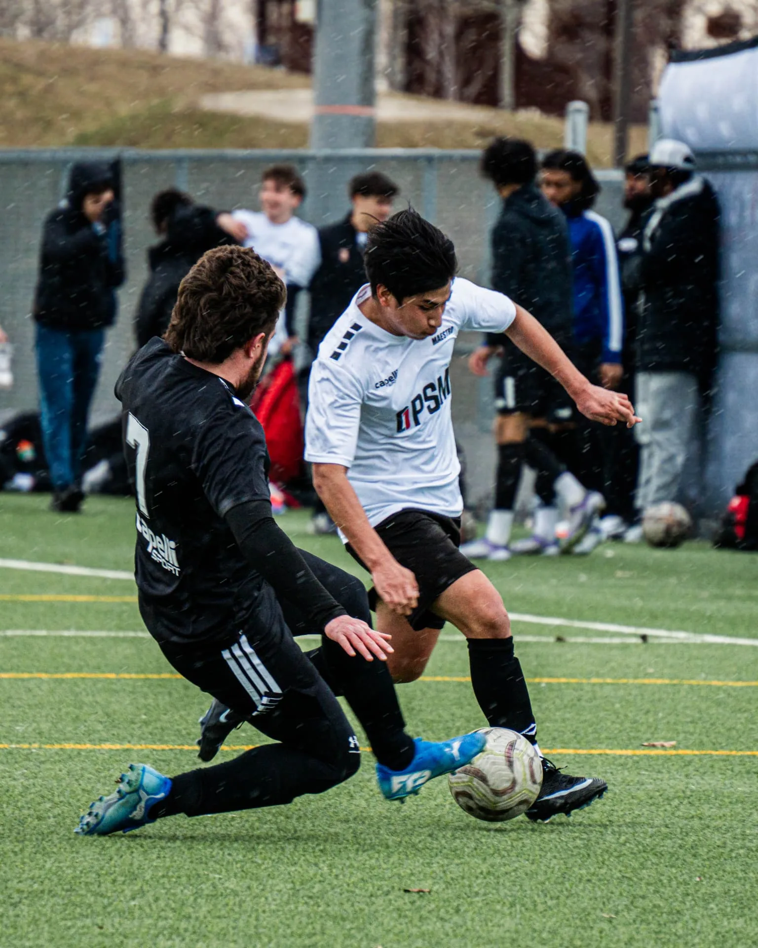 Winger cutting inside past a sliding defender in the rain