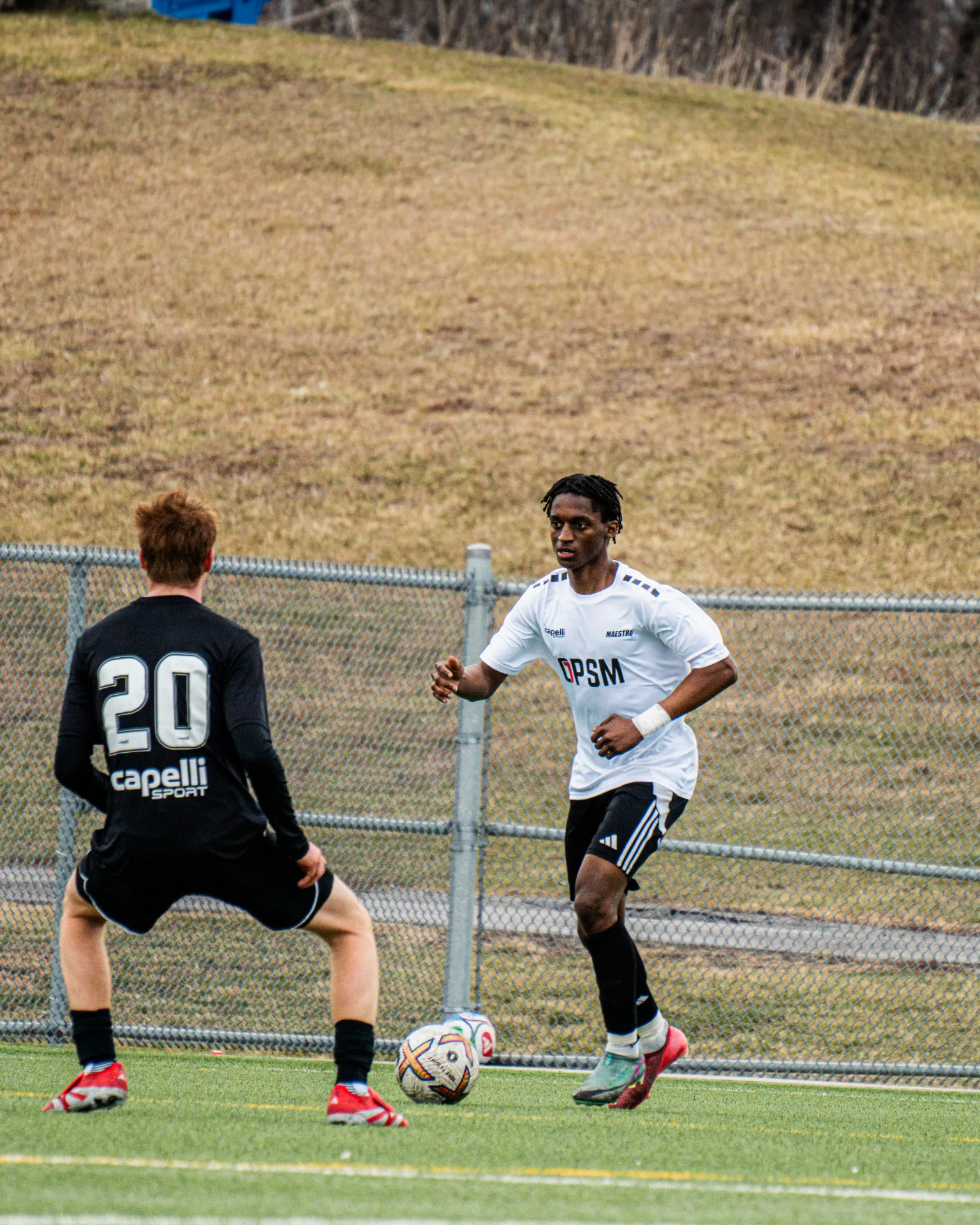 Player in white OPSM kit taking on a defender