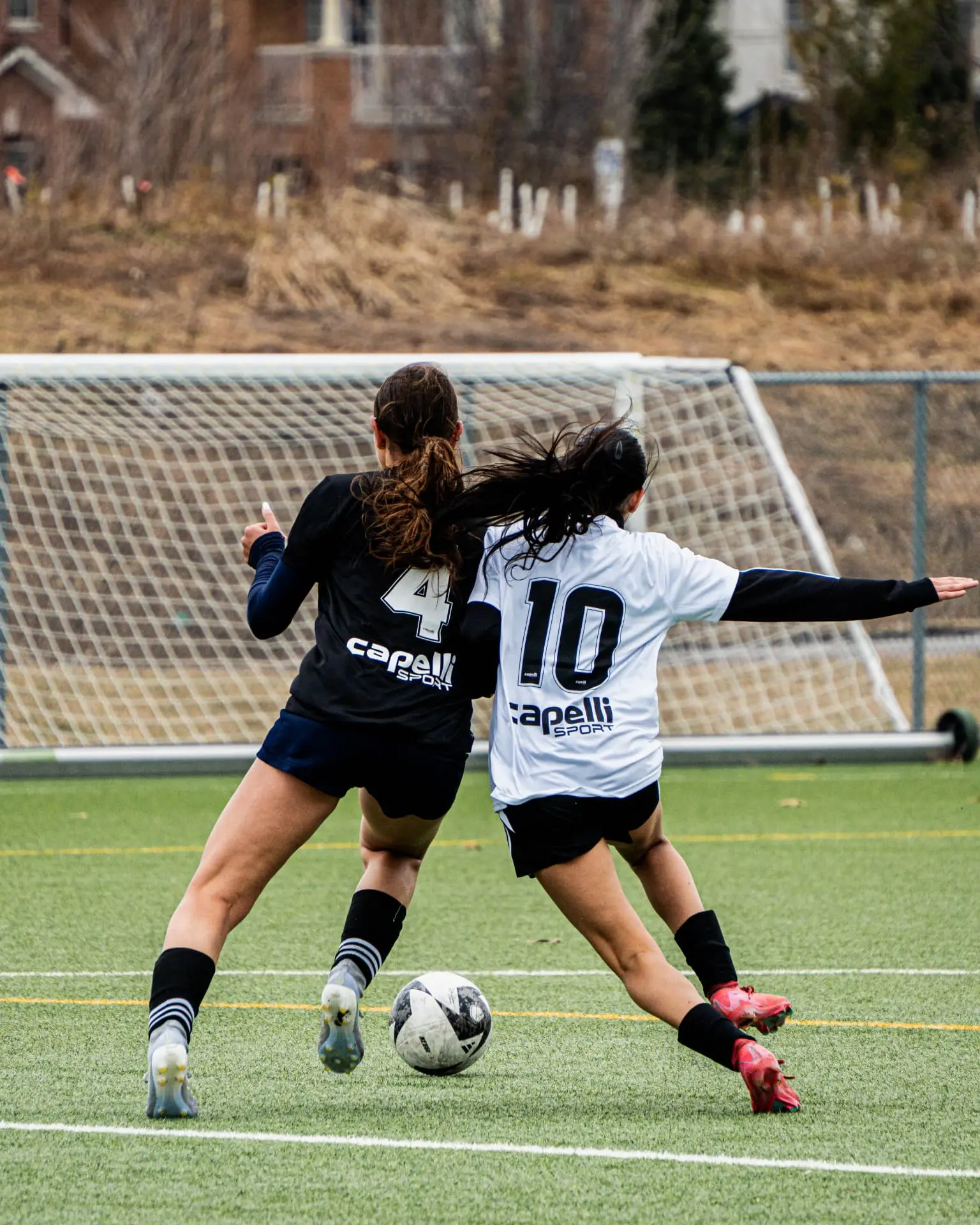 Two players battling shoulder to shoulder near the goal